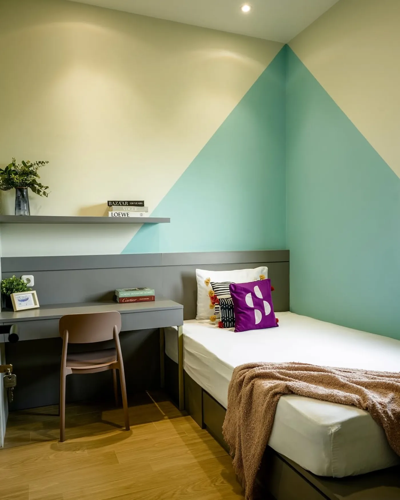 Boarding house room with a bed, desk, and painted feature wall