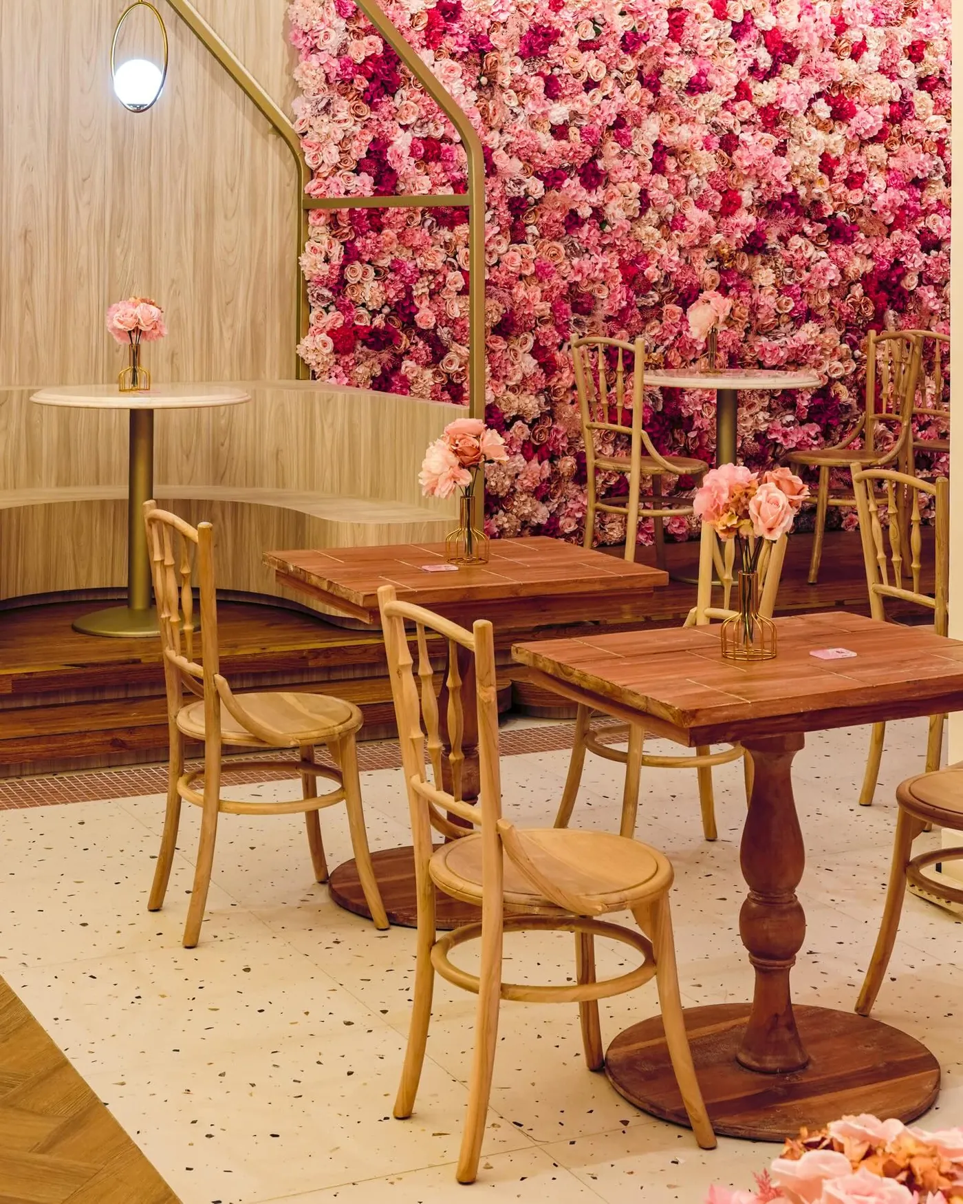 Cafe seating in front of a pink flower wall with brass framing