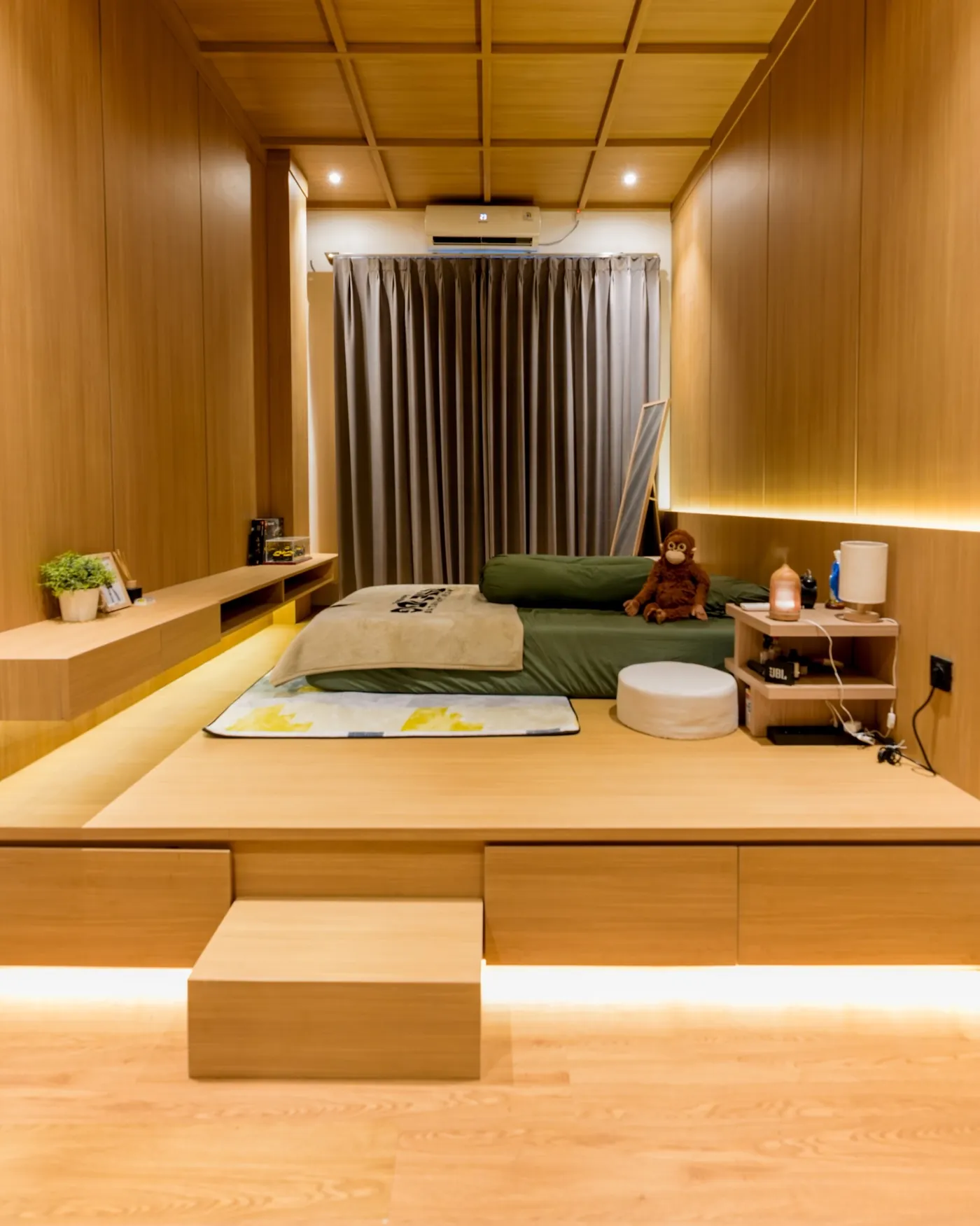 Bedroom lined in warm wood with a raised platform bed and indirect lighting
