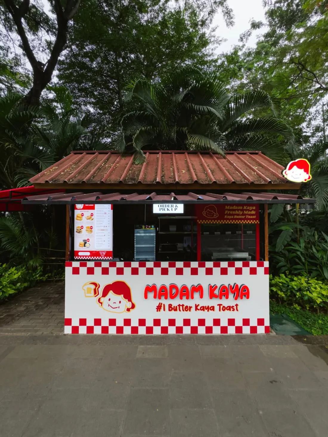 Small food tenant with a red and white facade under trees